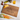 A personalized cutting board crafted from rich walnut wood engraved with the names “George & Megan” and “Est. 2024,” accented by a monogram “G M” surrounded by leafy botanical details. The board rests on a white surface with green and red grapes, a bottle of wine, a glass of golden white wine, crackers, cubes of cheddar cheese, and heirloom carrots. This elegant custom cutting board doubles as a stylish serving board and makes a timeless cutting board gift for weddings, anniversaries, and housewarmings.