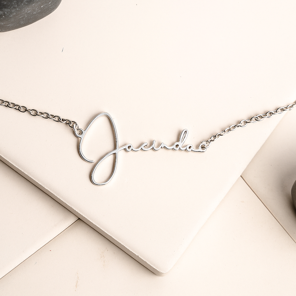Silver necklace with a nameplate on a light surface with stones