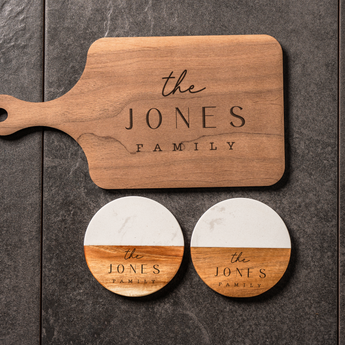 Wooden cutting board and coasters with 'the JONES FAMILY' engraving on a dark surface